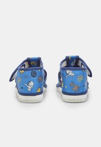 Sinised väikeste laste kingad loomapiltidega, sealhulgas elevandid, lõvid ja hirved, nähtavad tagantpoolt, avatud Velcro rihmadega.