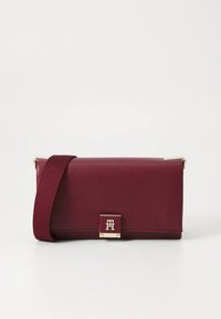 Bordeaux texturen leren handtas met een magnetische sluiting, gouden hardware en een gevlochten riem. Rechthoekige vorm, minimalistisch ontwerp.