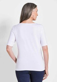 Witte korte mouwen top met een ronde hals, een gladde textuur en een relaxte pasvorm, gecombineerd met donkerblauwe broek.