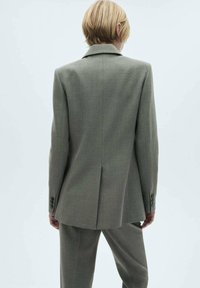 Giacca da abito grigia su misura con rever a punta, due bottoni e spalle strutturate. Presenta un design pulito e minimalista e una consistenza media.