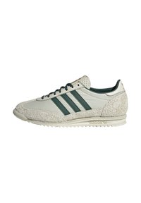 Tenisky Adidas s vrchnou časťou z svetlo sivej kože, textúrovanými sivými semišovými akcentmi, zelenými pruhmi a bielou gumovou podrážkou.