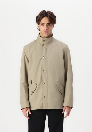 Beige wasserdichte Jacke mit hohem Kragen, Druckknöpfen und schrägen Fronttaschen. Eine glatte Textur und ein minimalistisches Design mit subtiler Markenkennzeichnung.