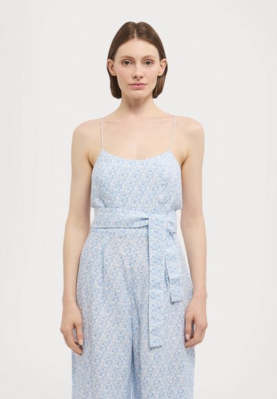 Jumpsuit floral em azul claro com alças finas, faixa na cintura, pernas largas e textura subtil. Apresenta um delicado padrão floral em azul mais escuro.