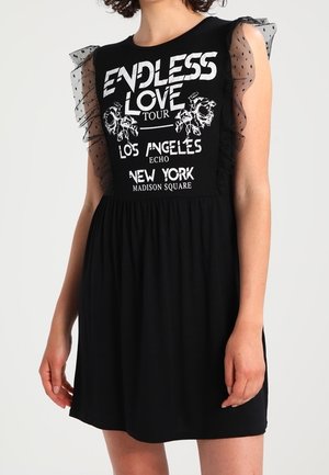 Černé šaty s potiskem na přední straně s nápisem "ENDLESS LOVE TOUR", průsvitné rukávy s volánky a rozšířená sukně. Hladká látka, ležérní styl.