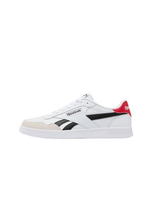 Witte Reebok sneaker met zwarte strepen, beige teenaccent, rode hieltab en witte zool getoond in zijaanzicht.