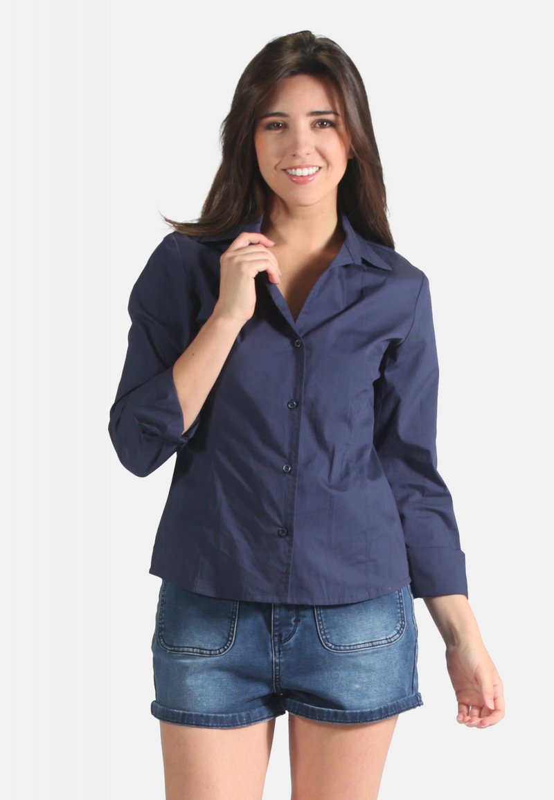 Chemise bleu marine à boutons en tissu doux, dotée d'un col, de manches longues et d'un ourlet courbé. Associée à un short en denim.