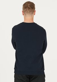 Mörkblå sweatshirt i texturerad tyg. Rundad halsringning, ribbade ärmslut och nederkant. Enkelt design utan synliga mönster eller logotyper.