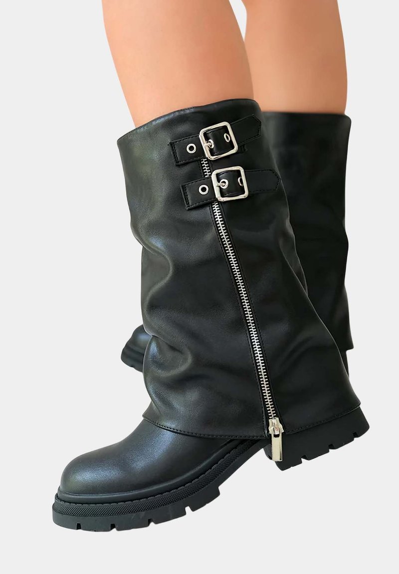 Bottes noires en cuir montantes avec un design décontracté, comportant des éléments en métal argenté, deux accents de boucle et une fermeture éclair sur une semelle texturée.