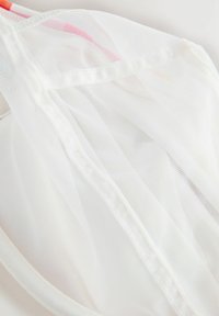 Balts tīklojuma audums ar smalku, caurspīdīgu tekstūru. Tam ir gluda, mīksta mala un smalkas šuves detaļas gar malām.