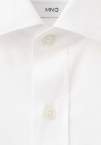 Biała koszula na guziki z klasycznym kołnierzykiem, z pojedynczym kremowym guzikiem i metką z napisem "MNG" wewnątrz kołnierza. Gładka tekstura.
