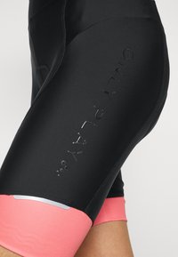 Czarne szorty rowerowe z różowym pasem, z wytłoczonym logo oraz gładkiego, elastycznego materiału dla wygody i swobody ruchów.