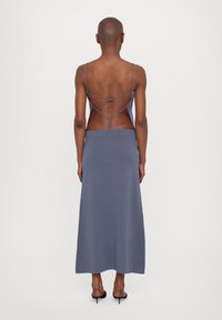 Long blue knit dress with a fitted bodice, spaghetti straps, and a crisscross back detail. Features a straight maxi length and soft texture.