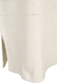 Maglione in maglia beige con una texture a coste, fessure laterali e un sottile motivo a pois lungo il bordo superiore.