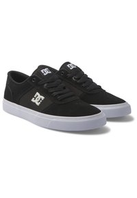 Black suede skate shoes with a white rubber sole and laces, featuring a prominent white DC logo on the side and ventilation holes on the toe.