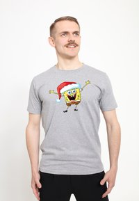 Šedé tričko s krátkým rukávem s grafikou Spongeboba v červené vánoční čepici s bílým lemem.