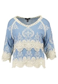 Himmelblaue Bluse mit Spitzenverzierungen. Verfügt über einen V-Ausschnitt, Dreiviertelärmel und filigrane Spitzenmuster am Saum und an den Ärmeln.