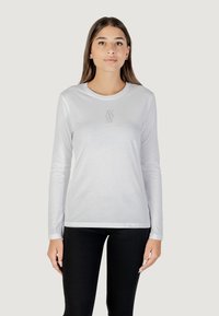 T-shirt bianca a maniche lunghe realizzata in tessuto liscio, con un piccolo dettaglio grafico grigio sul petto e design a girocollo.
