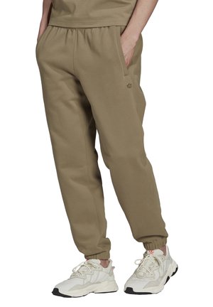 Vaaleanruskeat collegehousut, joissa on joustava vyötärönauha, sivutaskut ja pieni logokoriste. Yhdistetty paksuihin valkoisiin tennareihin.