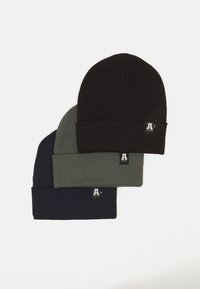 Three beanies stacked vertically: black, olive green, and navy blue. Each features a ribbed texture and a small logo tag on the cuff.