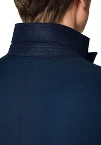 Niebieski płaszcz wełniany z kołnierzem o strukturalnym wzorze, z gładką teksturą i subtelnymi detalami przeszycia wzdłuż krawędzi.