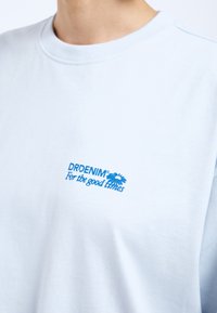 Hellblaues Baumwoll-T-Shirt mit Rundhalsausschnitt, mit blauer Logografie "DRDENIM" und "For the good times" auf der Vorderseite.