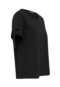 Must have lühikeste varrukatega must T-särk, mis on valmistatud pehmest kangast. Omab ümarat kaelust ja rulli käiselõikeid, mis on kinnitatud paelaga.