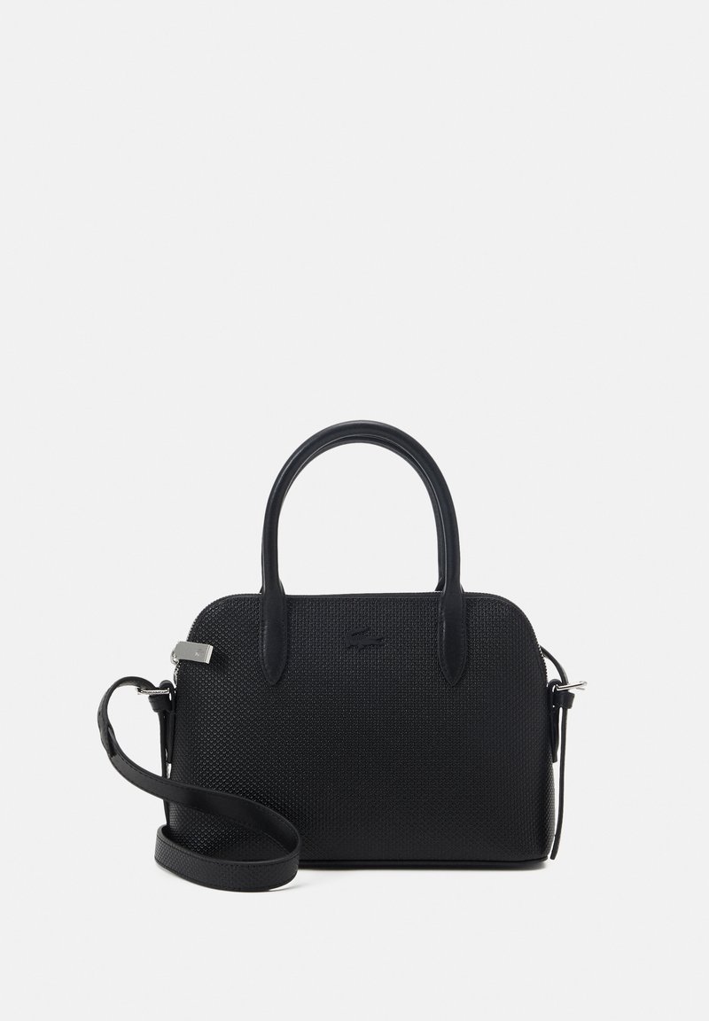 Sac à main noir texturé avec deux poignées et une bandoulière réglable sur un fond clair uni.