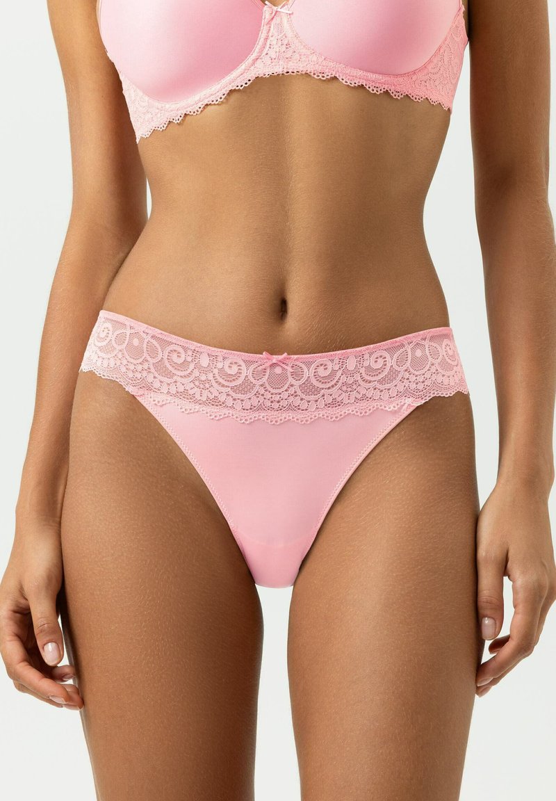 Roze ondergoed met kanten rand, voorzien van een glad katoenen lichaam en een uitbundige kanten band rond de taille, versierd met een klein strikdetail.