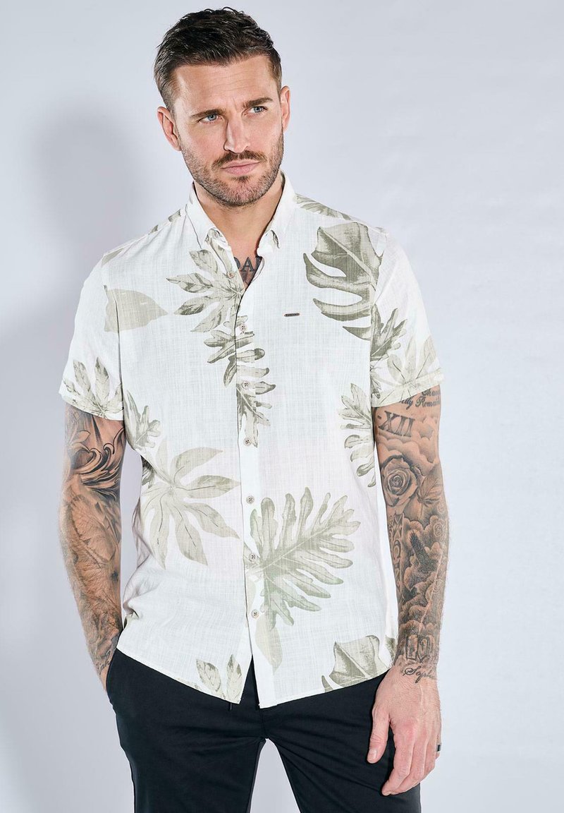Short-sleeve shirt featuring a white base with green leaf patterns, made from lightweight fabric, with a relaxed fit and button front.