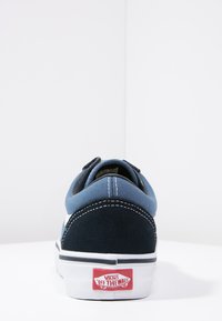 Plava i tamnoplava platnena tenisica s bijelom gumenenom petom, crnim šavom i crvenim logom "Vans Off The Wall" na peti.