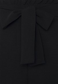 Tissu noir à texture lisse, avec un détail de ceinture nouée à la taille. Design simple sans motifs ni ornements visibles.