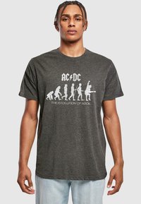 Grå bomulds t-shirt med et hvidt grafisk print af en menneskelig evolutionssekvens og teksten "AC/DC - Rockens Evolution."