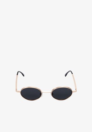 Lunettes de soleil ovales avec verres noirs et fines montures en métal doré, avec embouts noirs sur les branches incurvées.