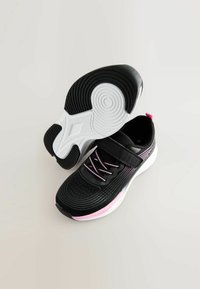 Baskets de sport noires avec une tige texturée, des accents roses, une semelle blanche et une sangle ajustable. Comprend des lacets et un design à bout rond.