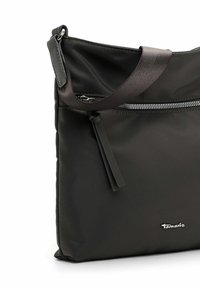 Sac à épaule noir en nylon avec une texture lisse, dotée d'une poche zippée, d'une sangle élégante et d'un petit accent de logo.