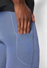 Αθλητικά σορτς Nike σε ανοιχτό μπλε με λεία υφή, διαθέτοντας πλαϊνή τσέπη και μαύρη ελαστική μέση.