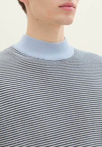 Niebieski i czarny sweter w paski z prążkowanym jasnoniebieskim kołnierzykiem. Tkanina ma teksturowaną powierzchnię, z poziomymi liniami na całej powierzchni.