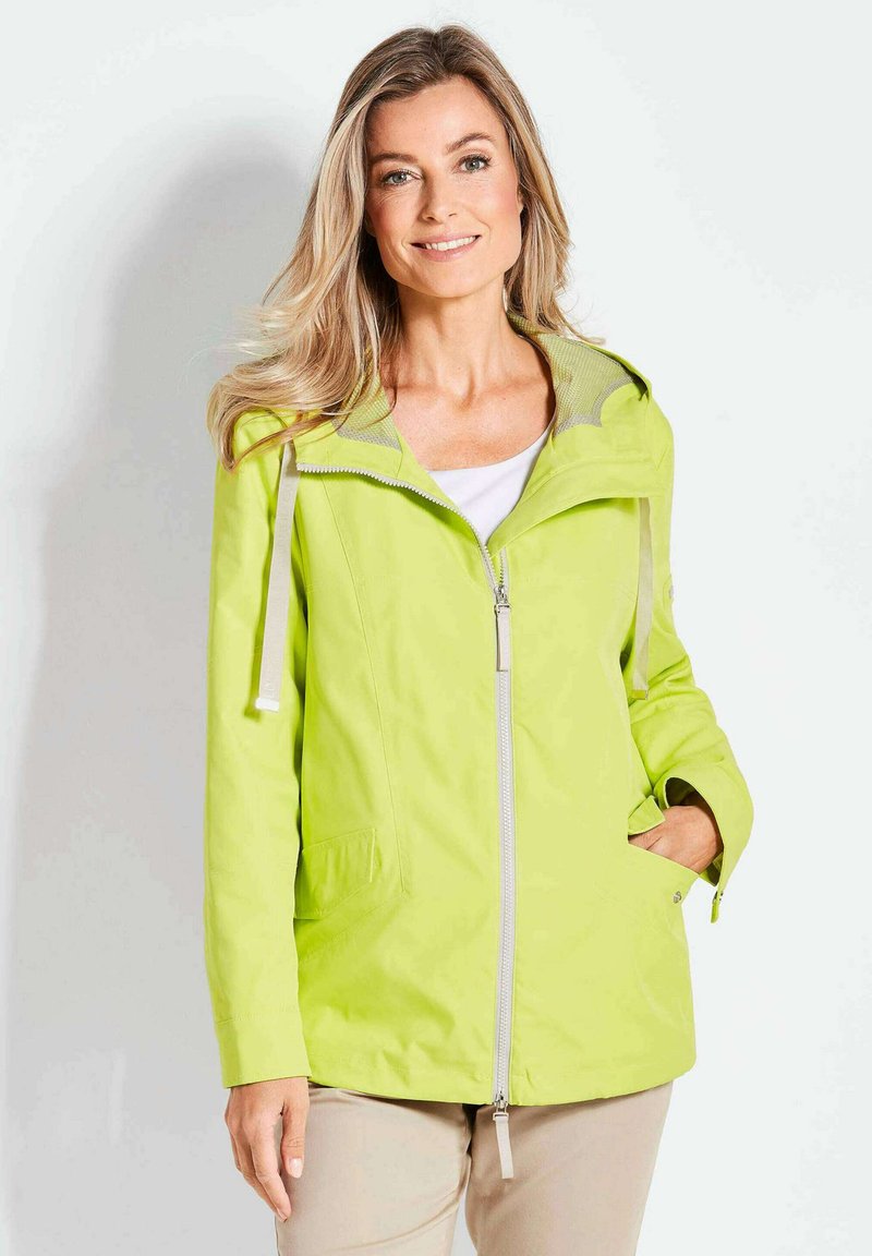 Helle limegrüne Jacke mit einem Reißverschluss vorne, Kapuze und zwei Seitentaschen. Glatte Textur mit kontrastierender Innenauskleidung.