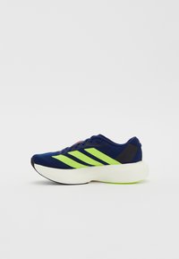 Pantofila sportivă albastră cu trei dungi neon verzi, superior din material texturat, talpă intermediară albă și accent negru pe călcâi. Design ușor.