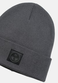 Gorro de punto gris hecho de material suave. Presenta un parche negro con logo circular de la marca y un diseño de puño doblado.