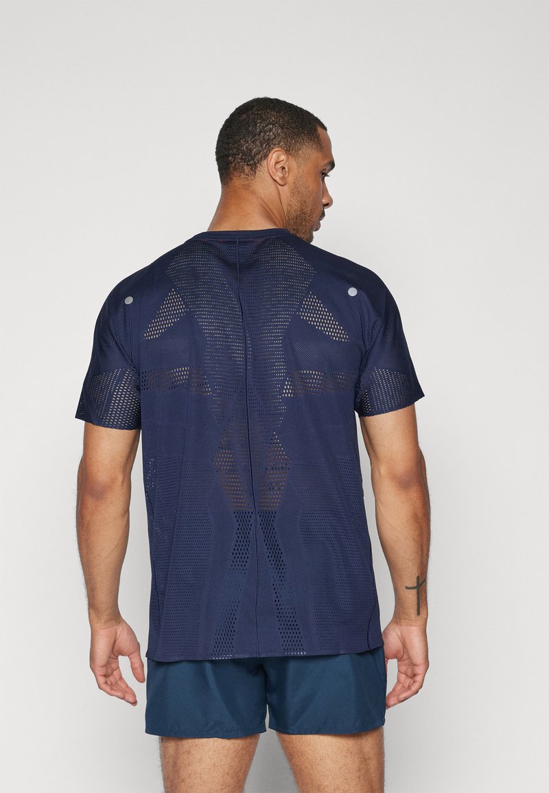 Marinefarbendes Sport-T-Shirt mit Mesh-Design, kurzen Ärmeln und einem strukturierten Muster. Enthält Akzentdetails, die eine Belüftung bieten.