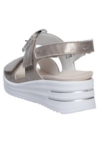 Silver suede sandal with an adjustable strap, cushioned footbed, and a white platform sole featuring metallic accents and cutouts.