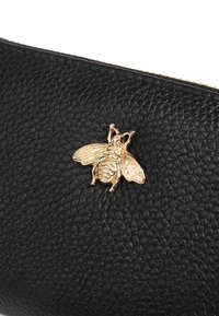 Portafoglio in pelle nera con superficie testurizzata e un emblema d'oro a forma di ape come dettaglio distintivo. Chiusura a zip nella parte superiore.