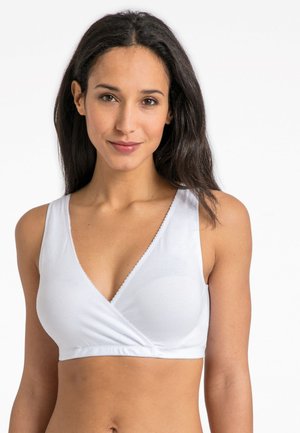 Biely braletový top vo style zabalenej podprsenky s hlbokým výstrihom do V, vyrobený z jemnej elastickej látky a s delikátne zúbkovaným lemovaním pozdĺž výstrihu a otvorov na ramenách.