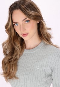 Maglione grigio a maglia con scollatura rotonda, dotato di un dettaglio ricamato a forma di ancora sul lato sinistro del petto. Tessuto morbido e texturizzato.
