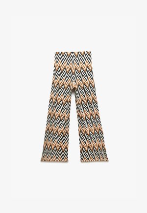 Schwarz-weiß-orange gestreifte, weit geschnittene Hose mit hoher Taille und fließendem Stoff, die ein markantes geometrisches Design bietet.