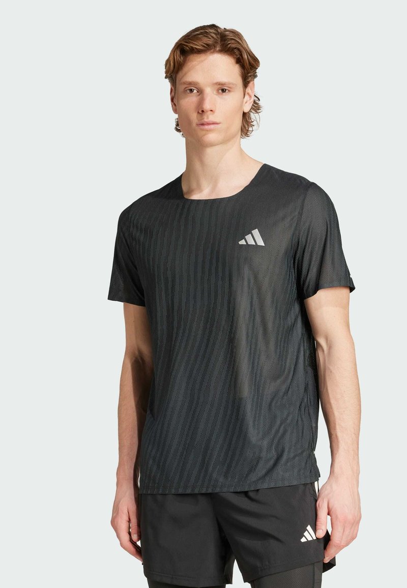 Camiseta deportiva negra con textura de rayas verticales, cuello redondo, mangas cortas y un logo reflectante de Adidas en el lado izquierdo del pecho.