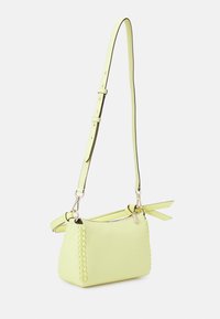 Bolso de hombro verde lima hecho de cuero texturizado, con un lateral trenzado y una correa desmontable de longitud ajustable. Detalles en madera.