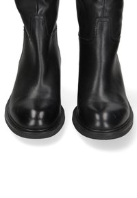 Stivali alla caviglia in pelle nera con punta arrotondata. Texture liscia, tacco basso e dettagli di cucitura sottili sui lati.