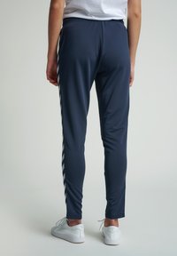 Marina atletiska byxor med slim fit, prydda med vita ränder längs sidorna, elastisk midja och mjukt, andningsbart tyg.